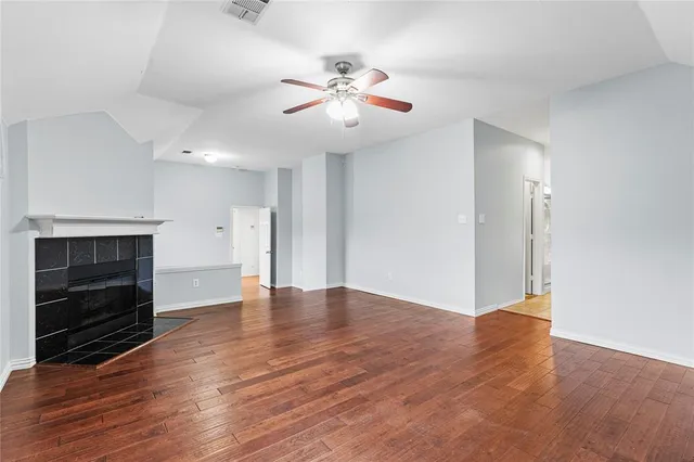 a view of an empty room with wooden floor fireplace and a window