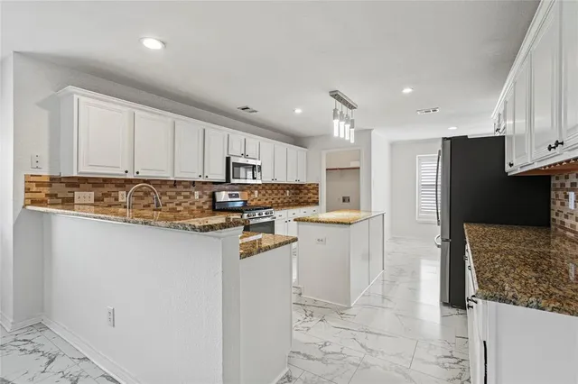 a kitchen with stainless steel appliances granite countertop a refrigerator and a stove top oven