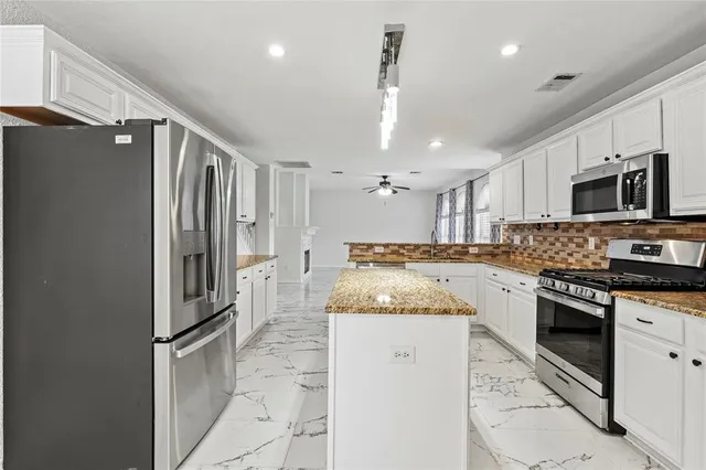 a kitchen with stainless steel appliances granite countertop a refrigerator a stove a sink and a microwave