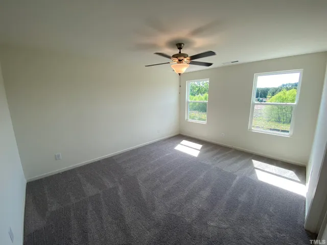 an empty room with windows and fan chandelier fan