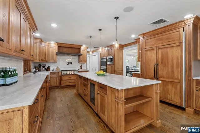 a kitchen with kitchen island granite countertop a sink a counter top space stainless steel appliances and cabinets
