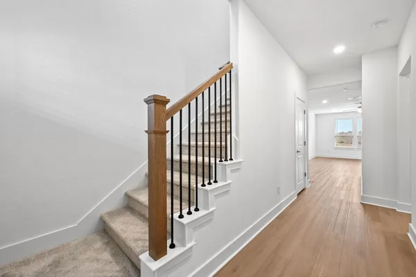a view of a hallway with wooden floor and staircase