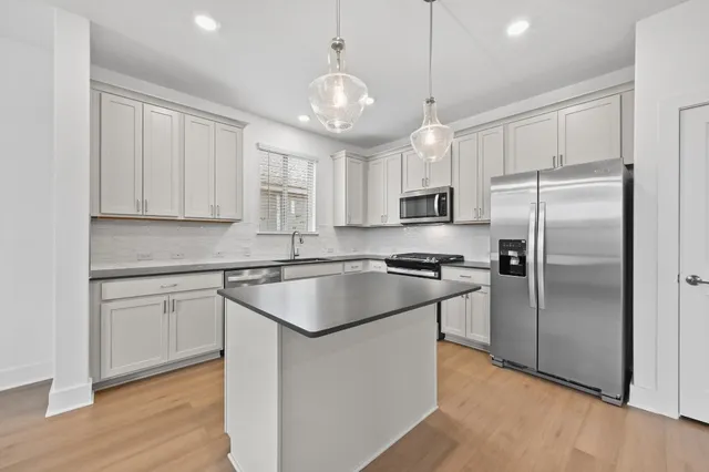 a kitchen with kitchen island a counter space a sink appliances and cabinets
