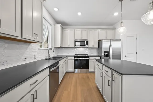 a kitchen with stainless steel appliances granite countertop a sink a stove a refrigerator and cabinets