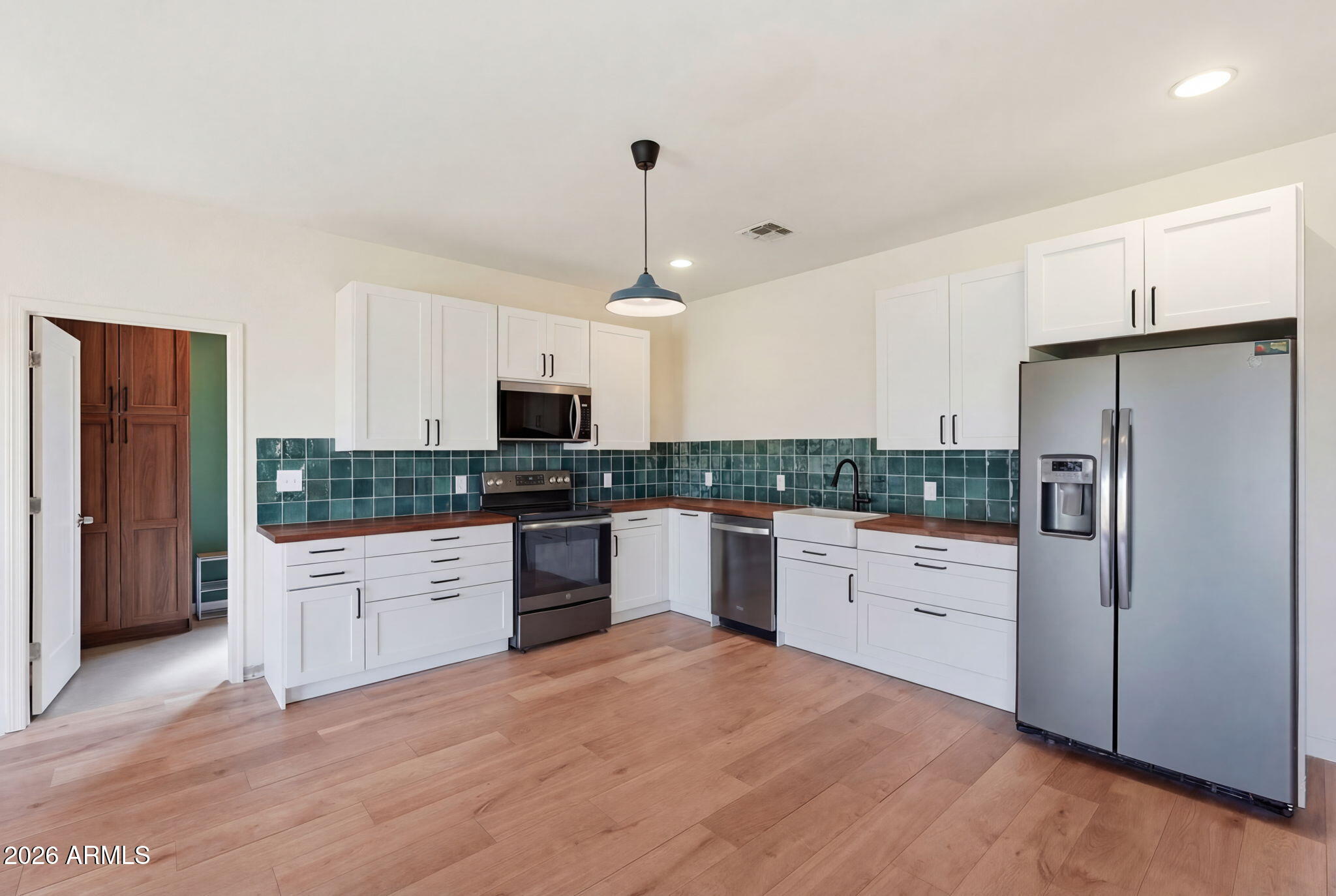 1289 South Oak Road Maricopa, AZ 85139 - Photo 12 of 39 a kitchen with granite countertop a refrigerator oven a sink dishwasher and white cabinets with wooden floor