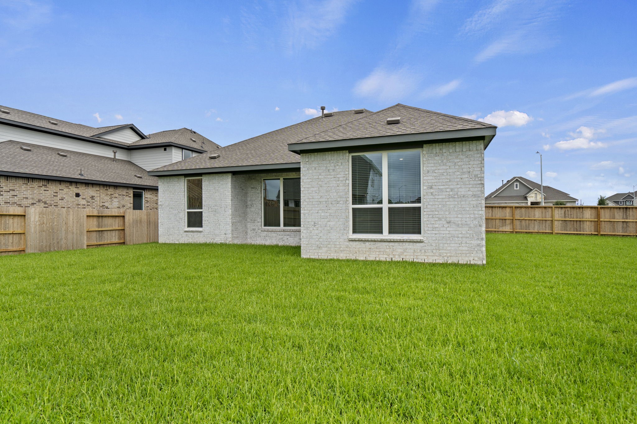 2720 Grove Crest Drive Rosenberg, TX 77469 - Photo 30 of 32 Rear exterior showcasing the home's modern brick elevation, covered patio, and expansive fenced backyard with room to enjoy outdoor living.