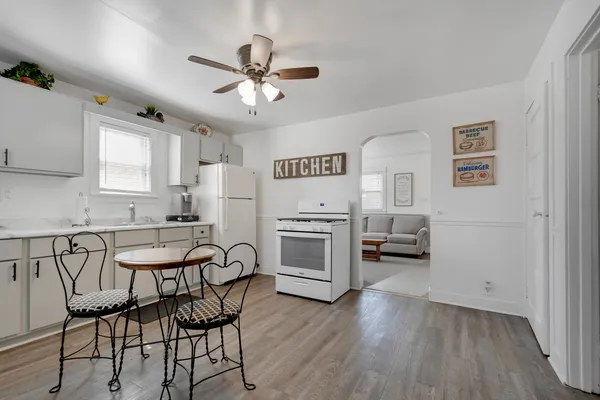 a kitchen with stainless steel appliances a stove a refrigerator and white cabinets with wooden floor