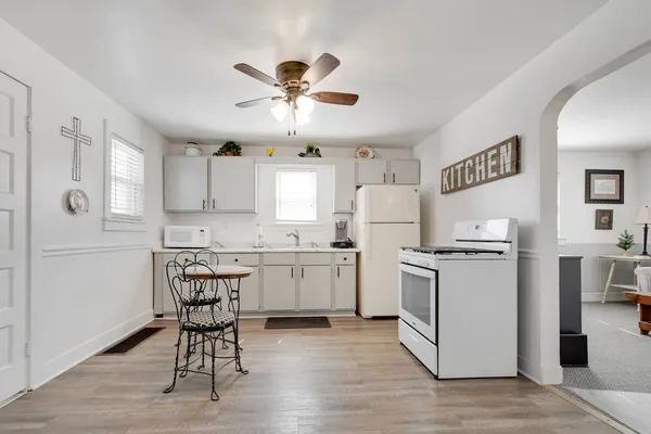 a kitchen with a refrigerator a stove cabinets dining table and chairs