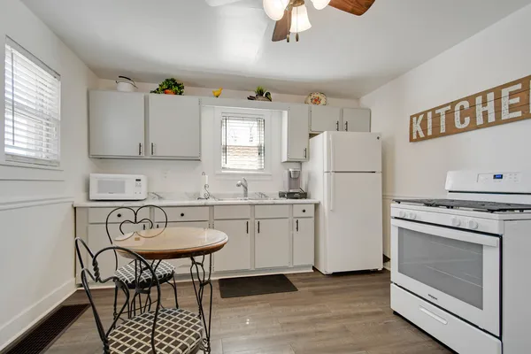 a kitchen with a refrigerator a stove a sink and a dining table with wooden floor