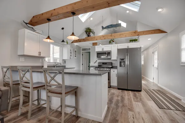 a kitchen with stainless steel appliances kitchen island granite countertop a table chairs in it and wooden floors