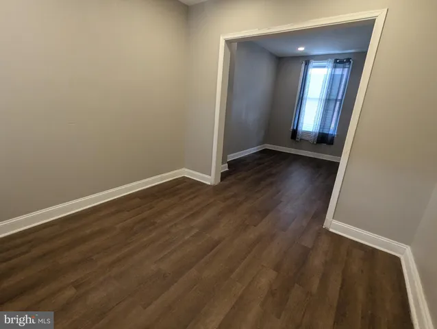 an empty room with wooden floor and mirror