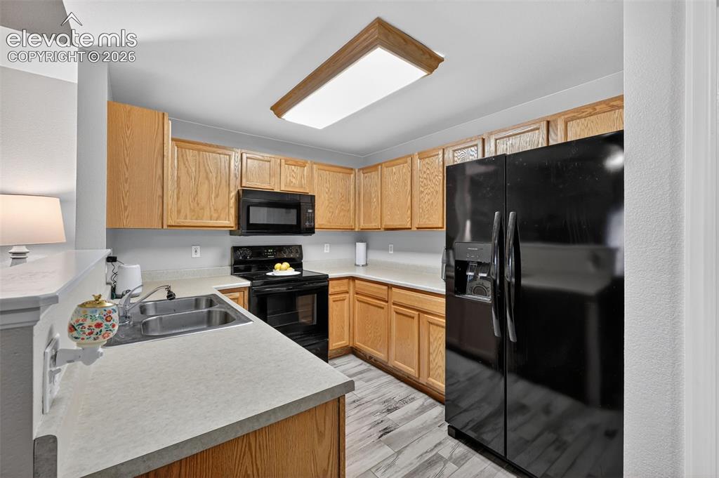 2141 Legacy Ridge View, Unit 109 Colorado Springs, CO 80910 - Photo 8 of 23 a kitchen with granite countertop a refrigerator stove top oven a sink and dishwasher