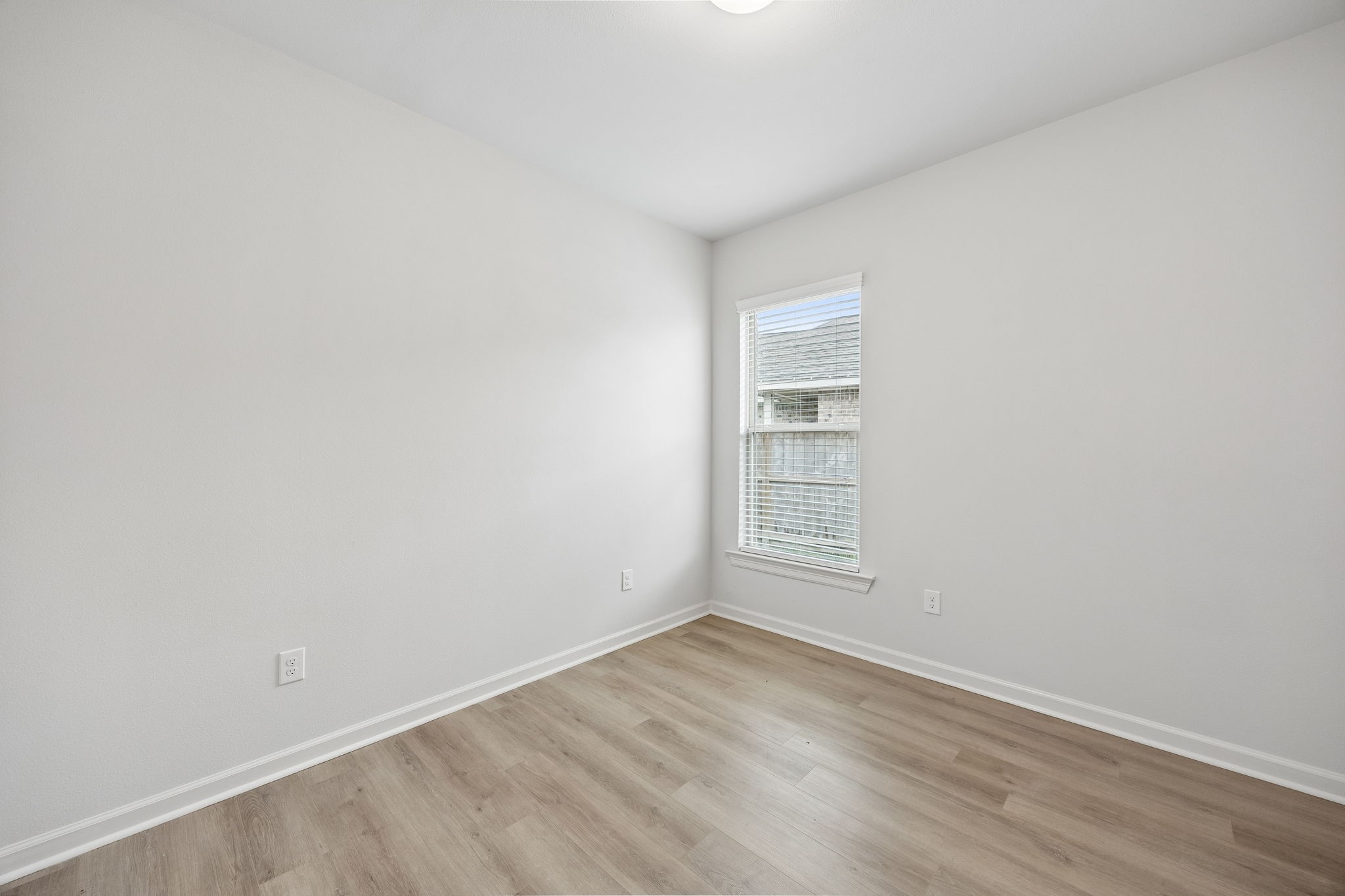 10902 Bonfire Trail Beasley, TX 77417 - Photo 17 of 36 This photo shows a bright, unfurnished secondary bedroom with neutral walls and light-color vinyl plank flooring. It features a window that lets in natural light, creating an airy atmosphere.