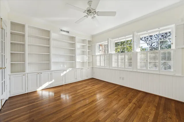 a view of empty room with wooden floor and fan
