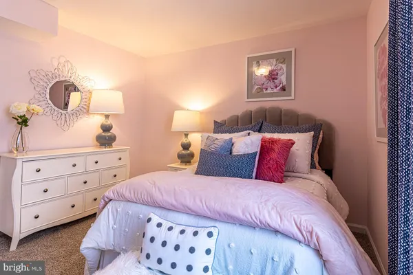 a bedroom with a bed and a lamp on dresser