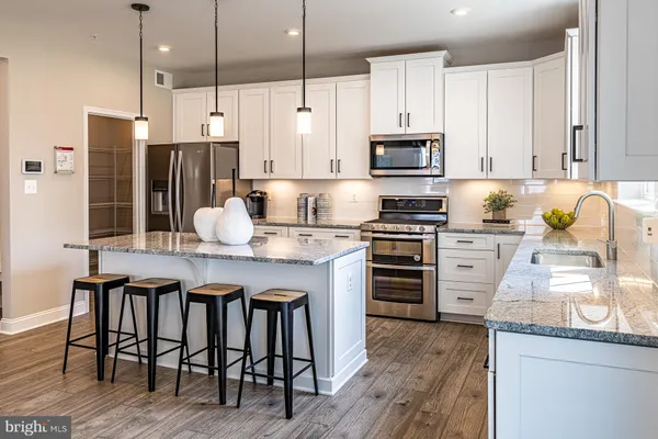 a kitchen with kitchen island granite countertop a table chairs stainless steel appliances and wooden floor