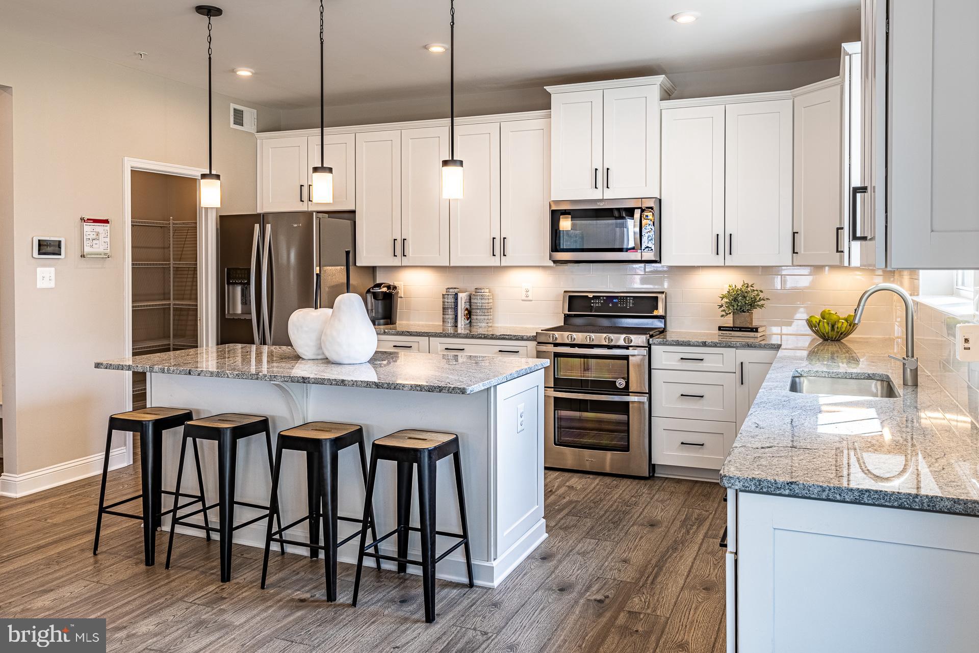 4004 Millner Road Nottingham, MD 21236 - Photo 2 of 34 a kitchen with kitchen island granite countertop a table chairs stainless steel appliances and wooden floor