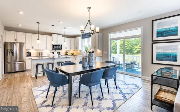 a dining room with stainless steel appliances kitchen island granite countertop a dining table chairs and a refrigerator