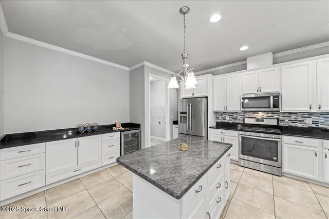 a kitchen with kitchen island granite countertop stainless steel appliances lots of counter top space cabinets and a refrigerator