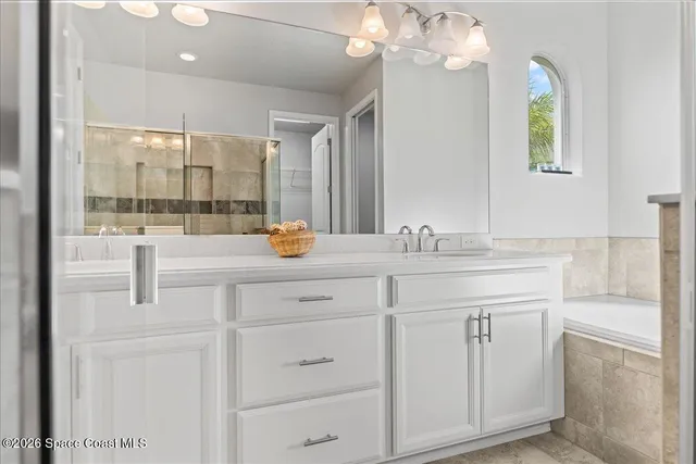 a bathroom with a double vanity sink mirror and a bathtub