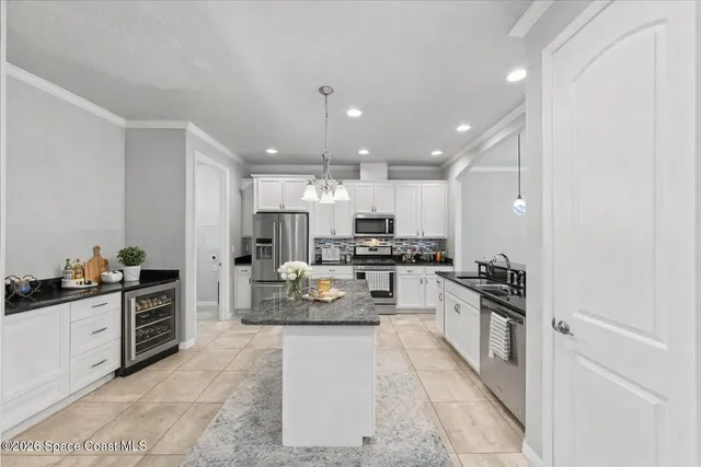 a kitchen with stainless steel appliances granite countertop a sink a stove a oven a refrigerator and white cabinets