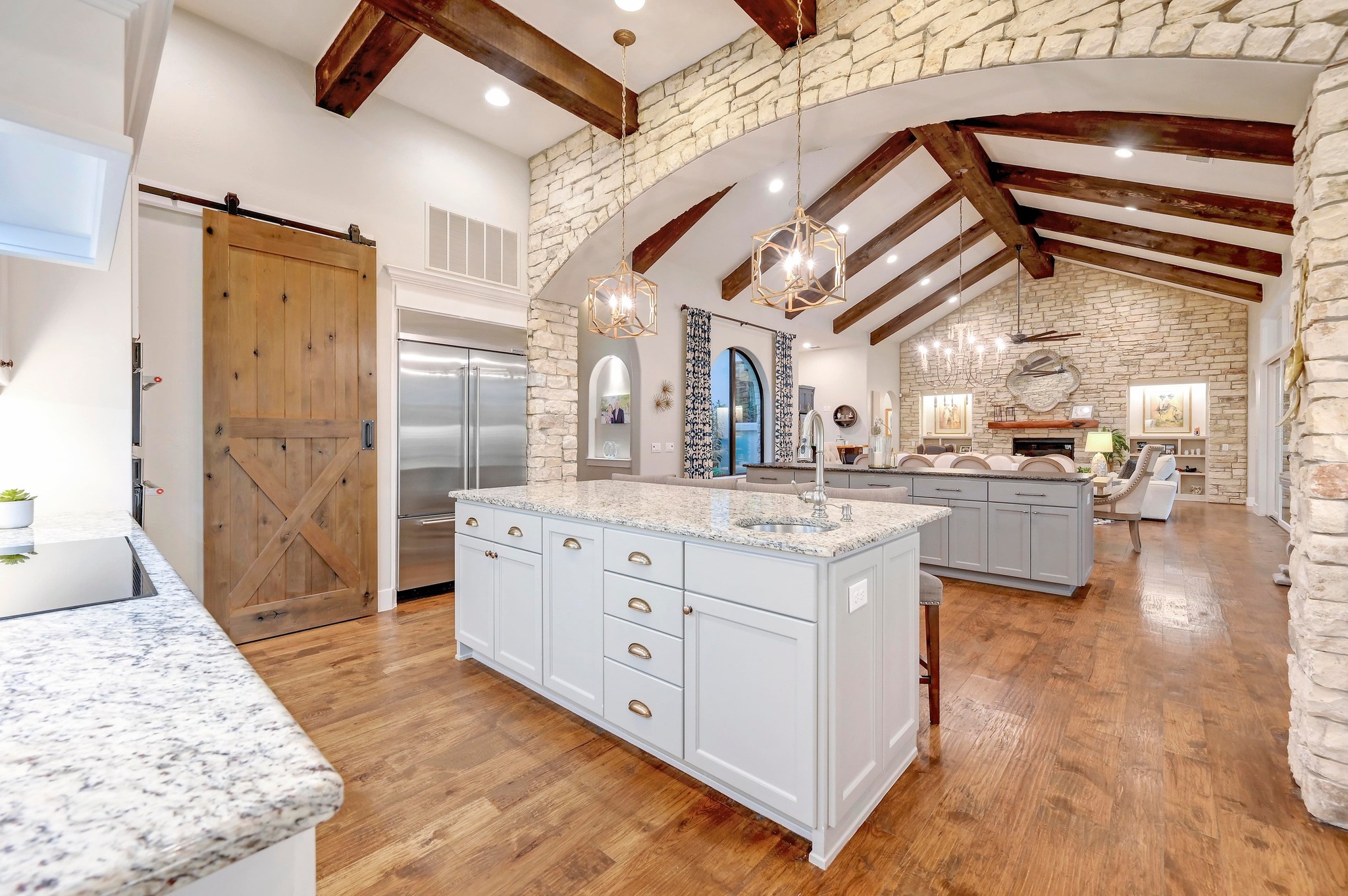 401 Trail Ridge Road Wimberley, TX 78676 - Photo 9 of 34 Kitchen featuring a barn door, white cabinets, beam ceiling, high vaulted ceiling, and a fireplace