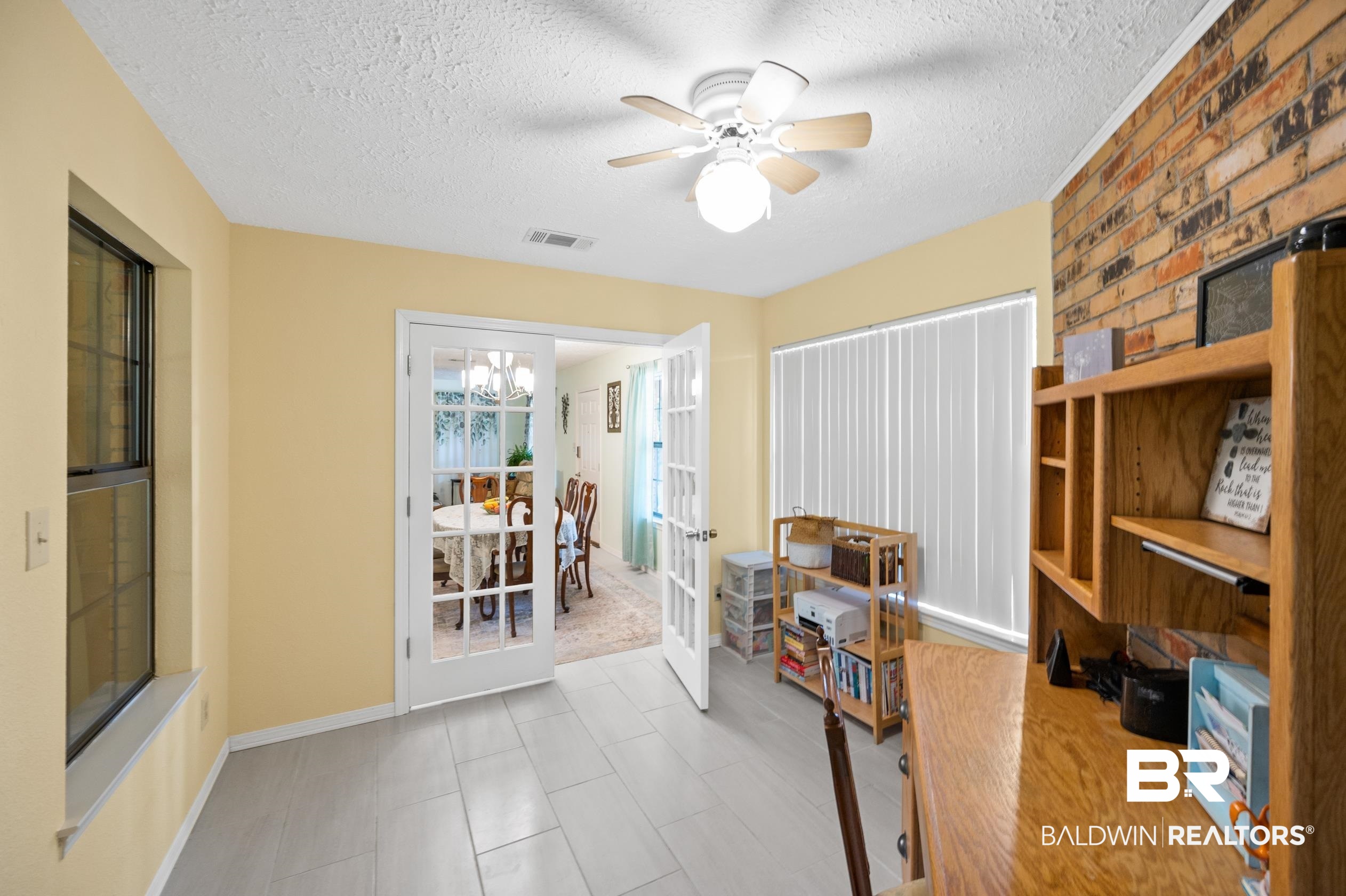 2772 Santa Rosa Circle Lillian, AL 36549 - Photo 26 of 50 Tiled office space featuring brick wall, a textured ceiling, ceiling fan with notable chandelier, and french doors
