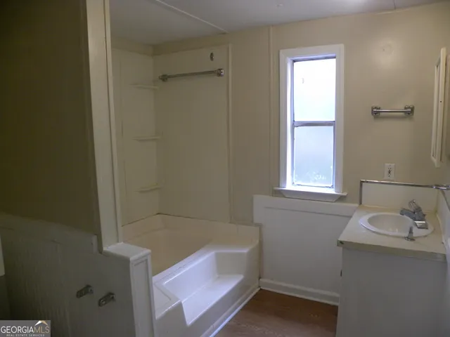 a bathroom with a tub shower sink and vanity