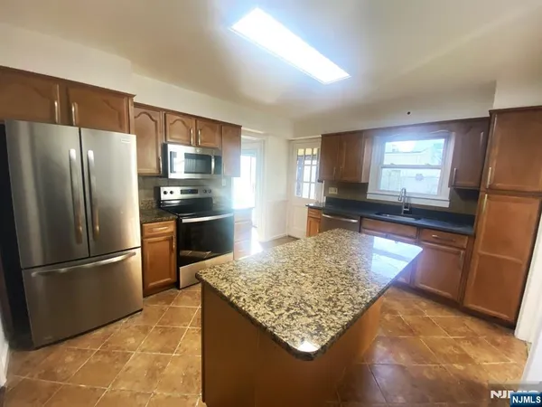 a kitchen with stainless steel appliances granite countertop a refrigerator sink and stove