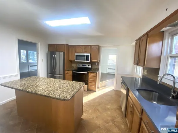 a kitchen with kitchen island granite countertop a sink stove and refrigerator