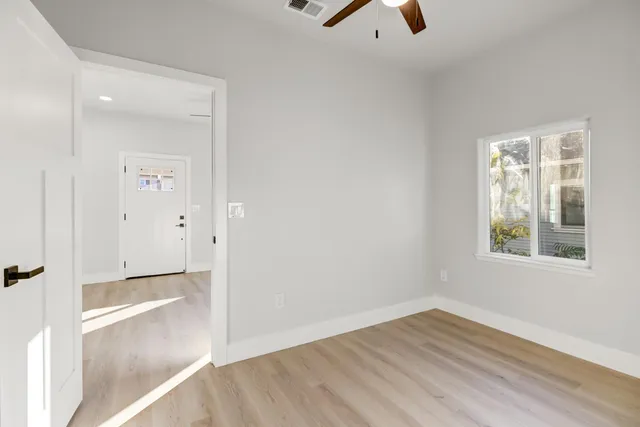 an empty room with wooden floor and windows