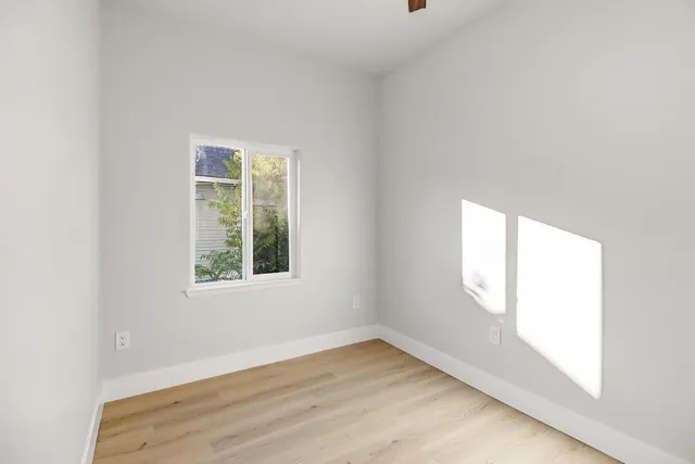 a view of an empty room with wooden floor and windows