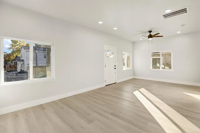 a view of an empty room with window and wooden floor