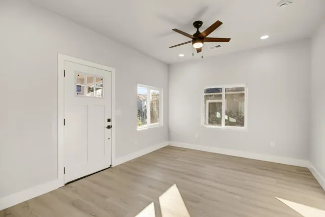 a view of an empty room with a window and wooden floor