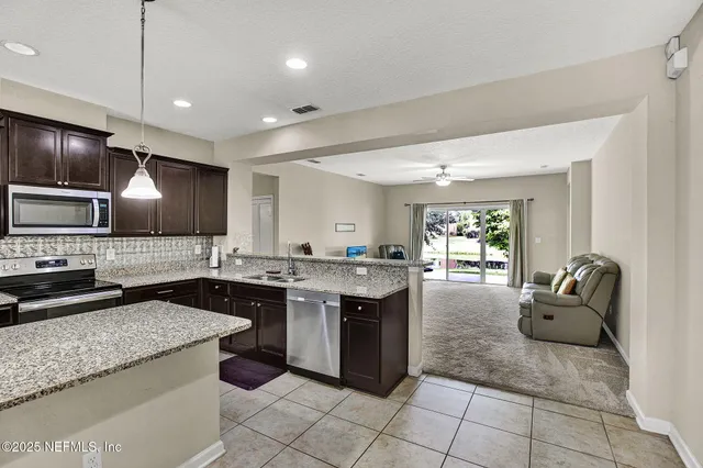 a large kitchen with stainless steel appliances granite countertop a sink and a counter top space