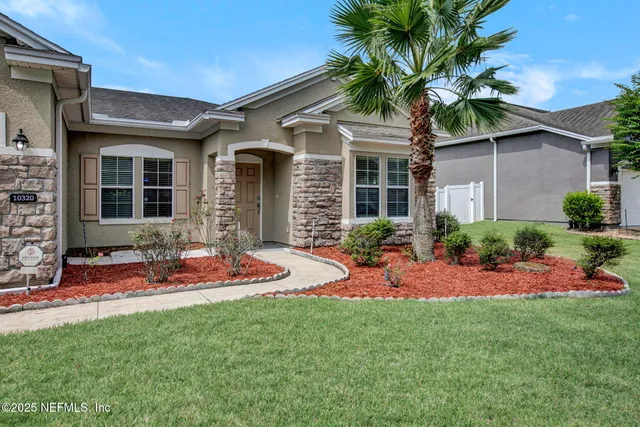 a front view of a house with a yard and potted plants