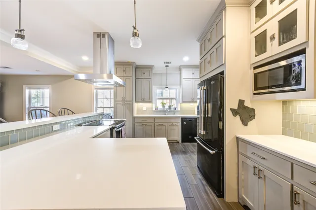 a kitchen with stainless steel appliances kitchen island granite countertop a refrigerator a sink dishwasher a oven with white cabinets and wooden floor