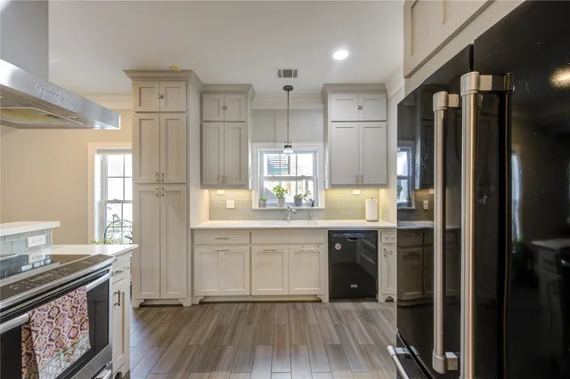 a kitchen with stainless steel appliances granite countertop a refrigerator a sink dishwasher a stove and white countertops with wooden floor