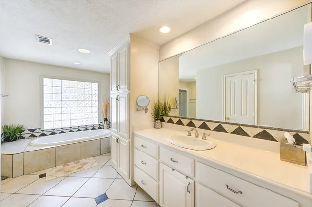 a spacious bathroom with a granite countertop sink a mirror and a bathtub