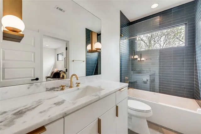 a bathroom with a granite countertop sink toilet mirror and bathtub