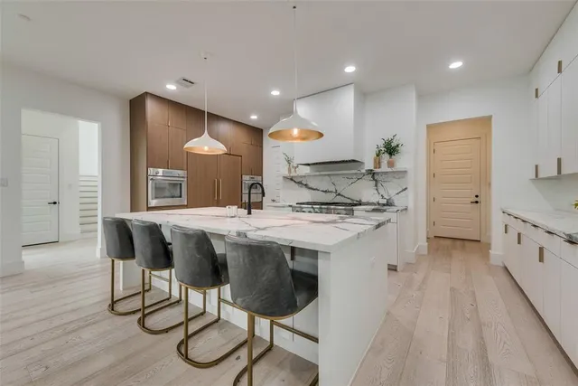 a kitchen with stainless steel appliances granite countertop a sink a stove a refrigerator and island with wooden floor