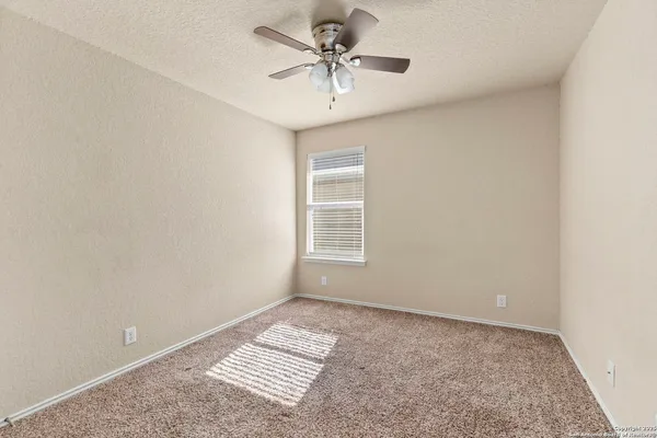 an empty room with a window and a ceiling fan
