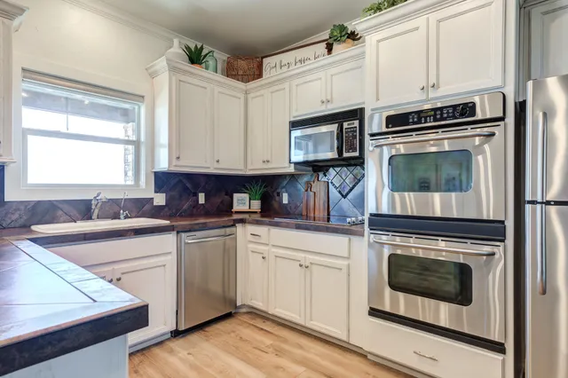 a kitchen with granite countertop white cabinets and stainless steel appliances