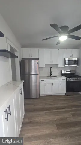 a kitchen with granite countertop a refrigerator a sink and white cabinets