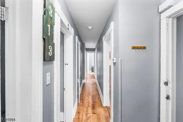 a view of a hallway with wooden floor and living room