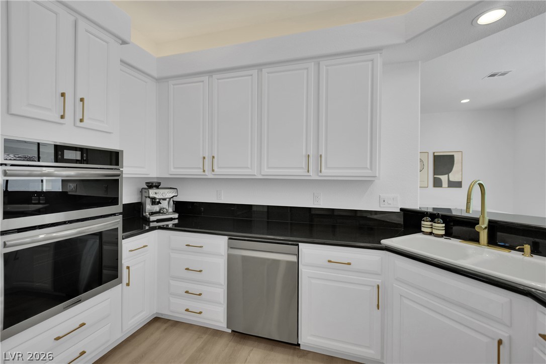8981 Rivers Edge Drive Las Vegas, NV 89117 - Photo 23 of 69 A well-appointed kitchen features white cabinetry and sleek black countertops.