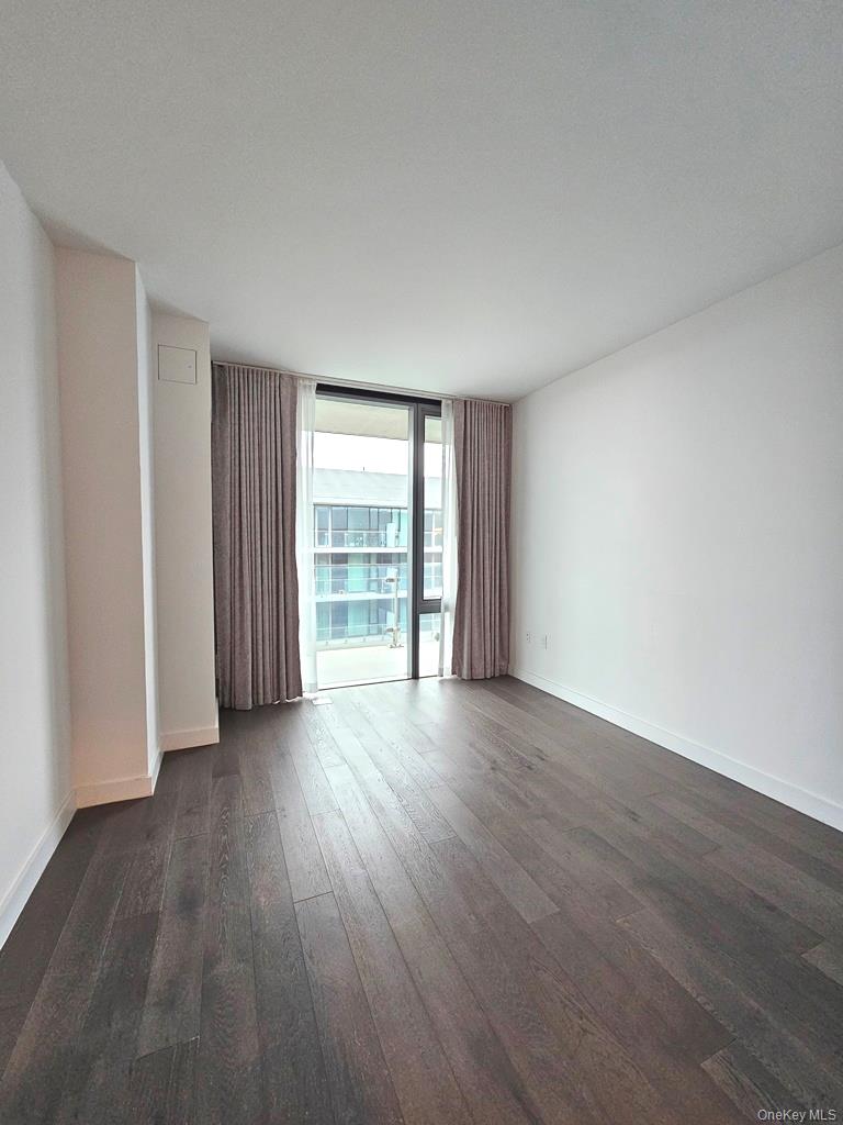 131-03 40 Road, Unit PH1Y Queens, NY 11354 - Photo 8 of 13 a view of an empty room with wooden floor and a window