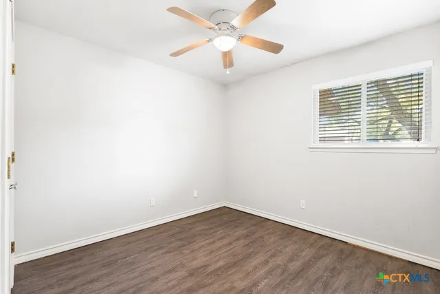 an empty room with a window and wooden floor