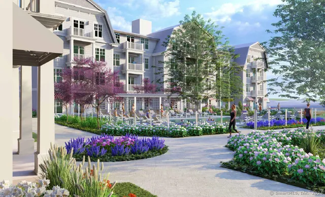 a front view of a multi story residential apartment building with yard and bench