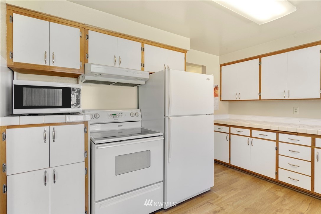 3322 Northeast 10th Place Renton, WA 98056 - Photo 10 of 21 a white refrigerator freezer and a stove sitting inside of a kitchen with granite countertop cabinets
